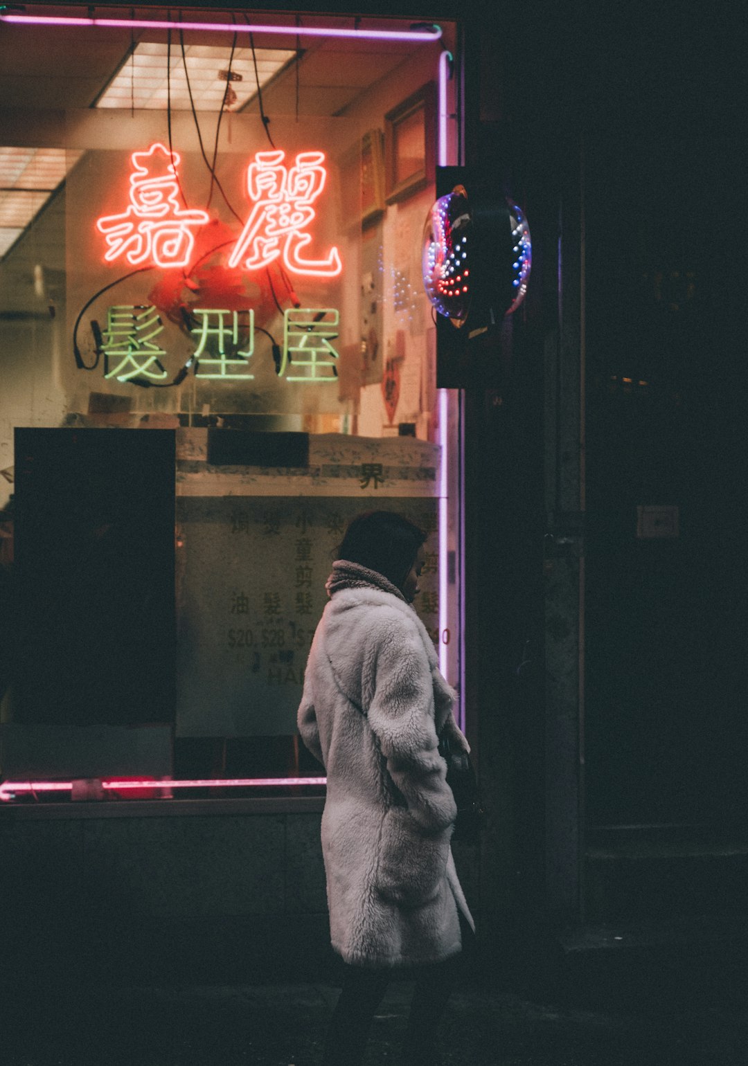 man in gray hoodie standing near red and white neon signage