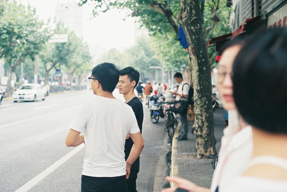 man in white crew neck t-shirt and black pants walking on street during daytime