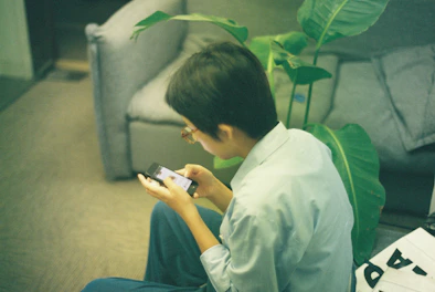 Persona usando un smartphone mientras está sentada en el suelo tomando terapia 