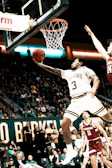 Dynamic basketball player mid-jump shooting towards the hoop in an intense game.