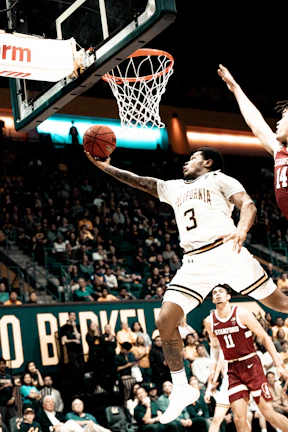 Dynamic basketball player mid-jump shooting towards the hoop in an intense game.