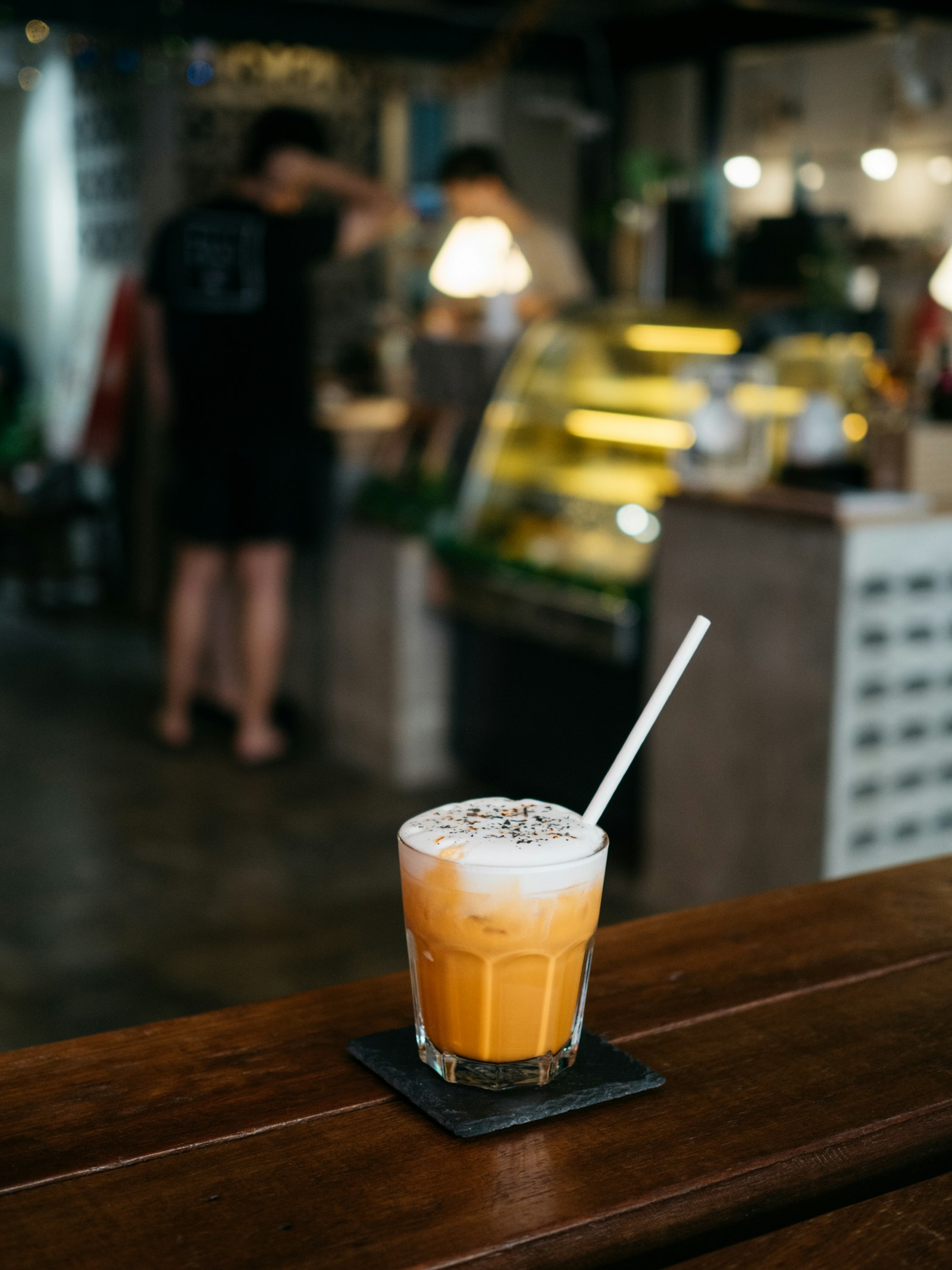 Thai iced tea on a caf&eacute; counter with a dessert cabinet behind
