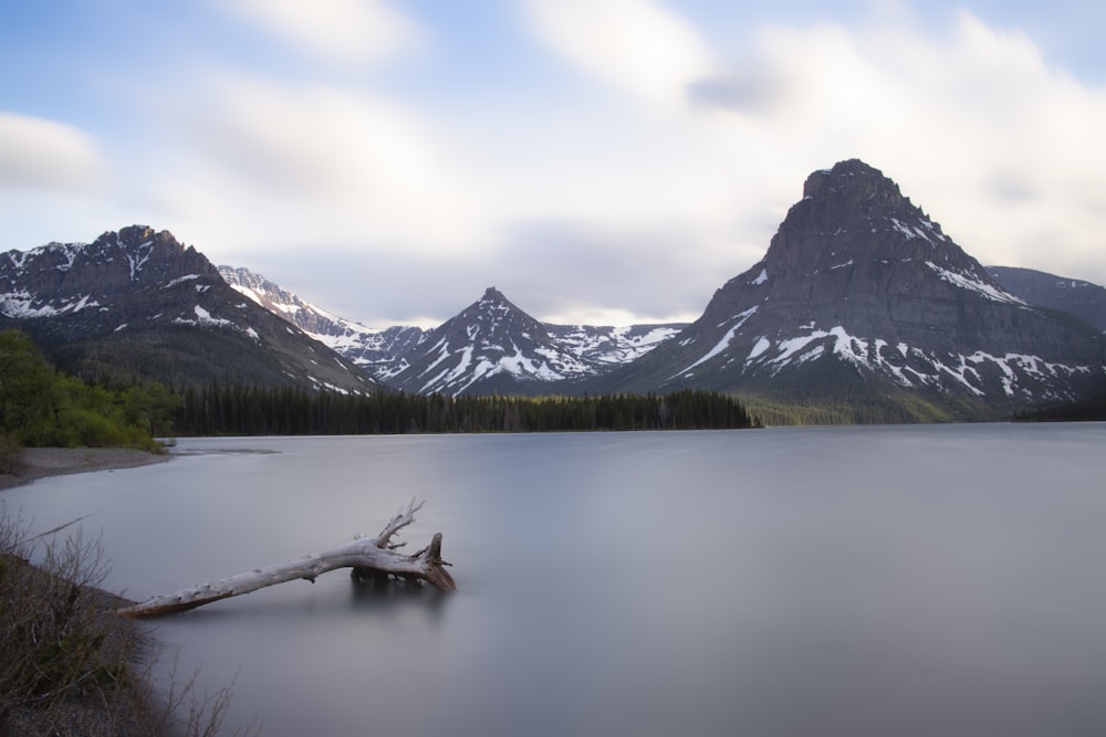 brown wooden boat on lake near snow covered mountain during daytime