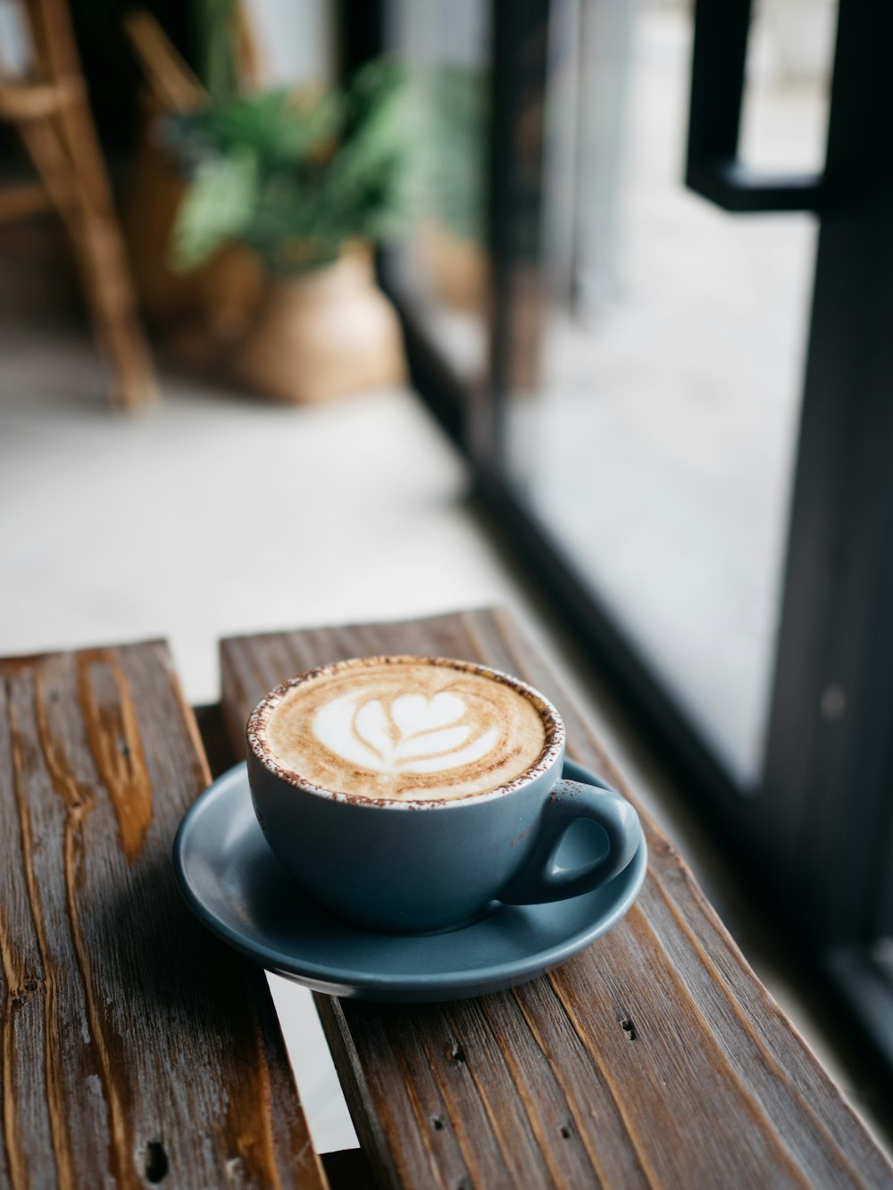 taza de cerámica blanca sobre platillo azul sobre mesa de madera marrón