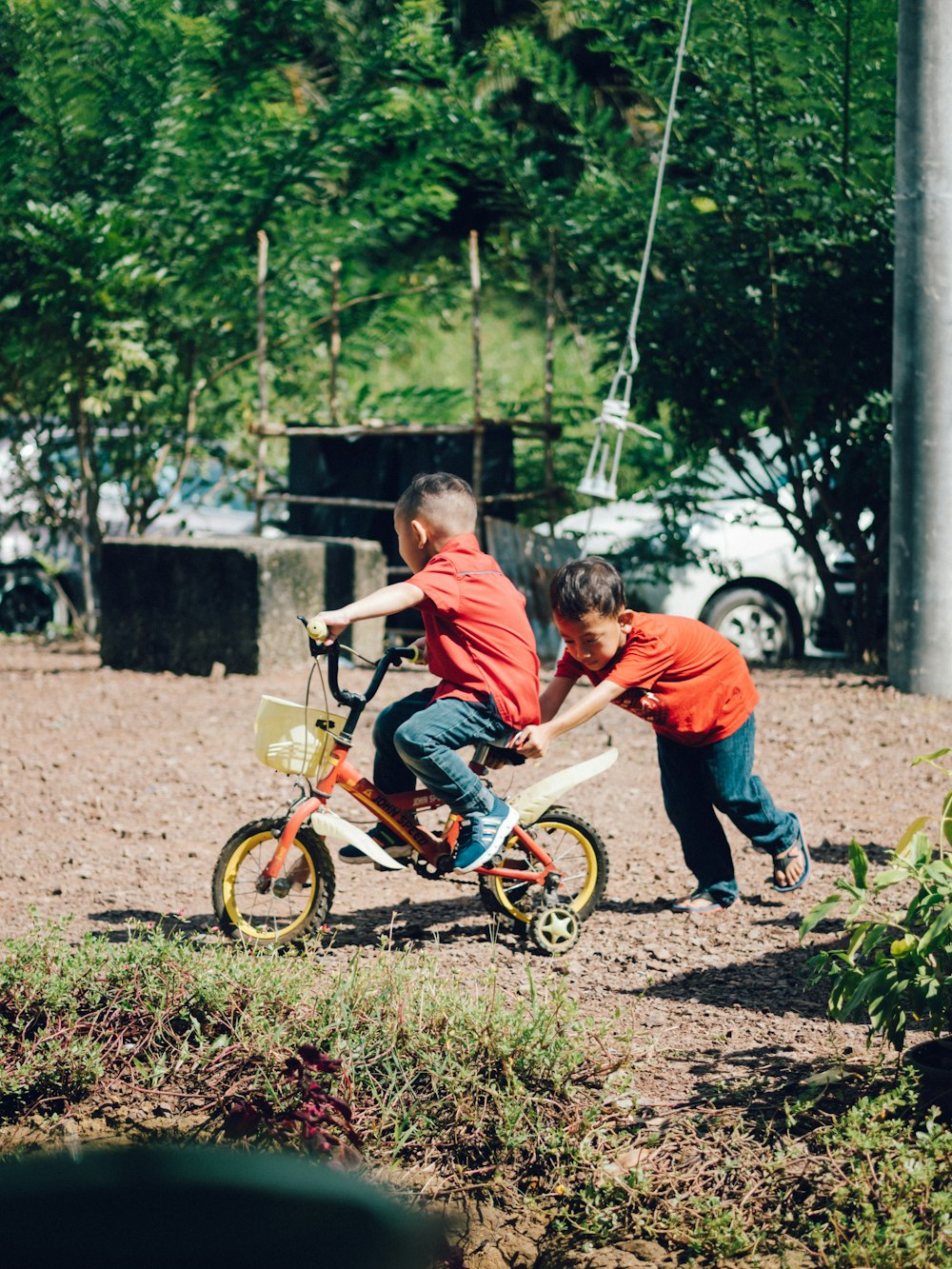 boy in orange t-shirt riding on bicycle during daytime