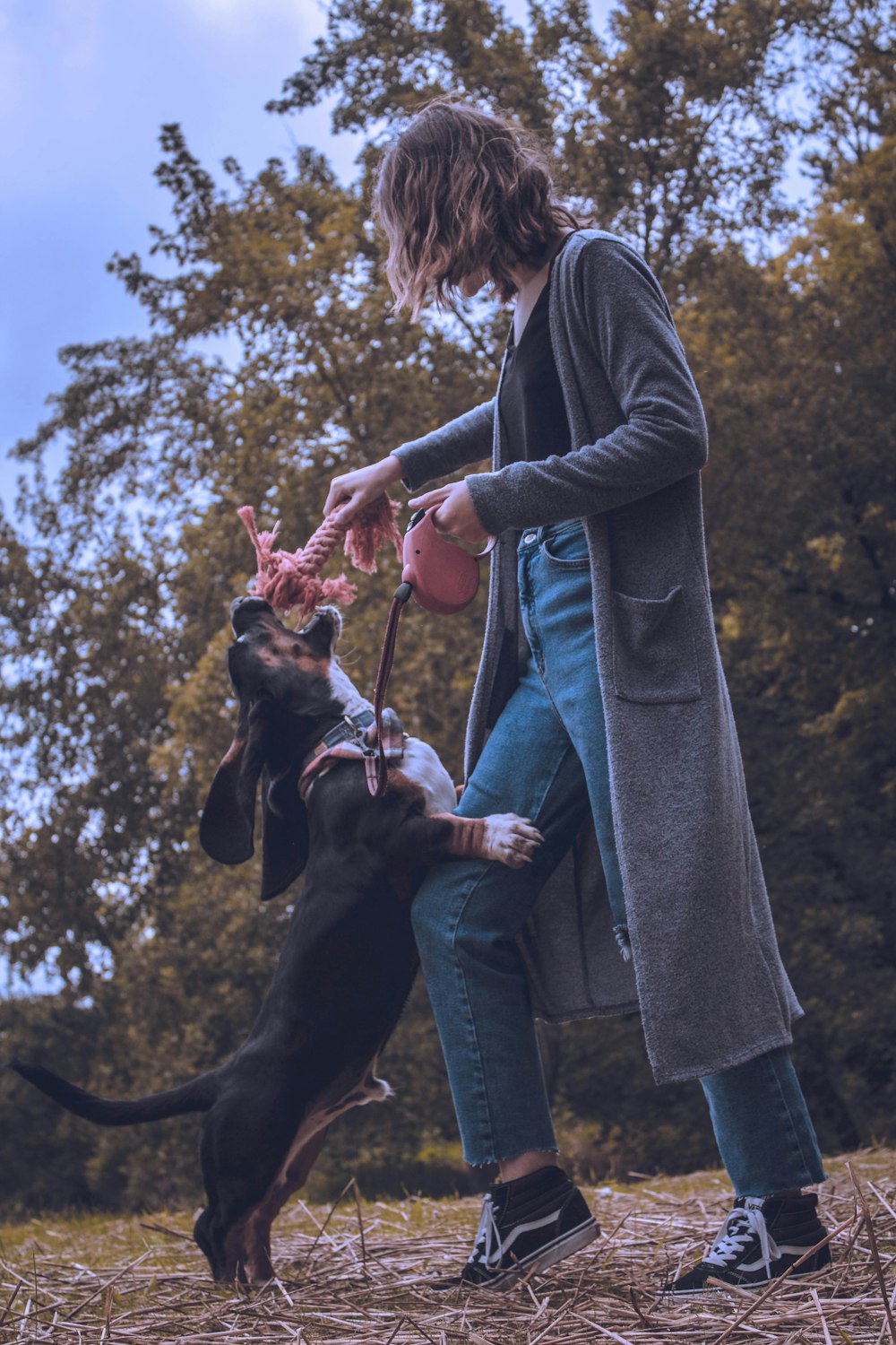 woman in black jacket holding black and brown short coated dog