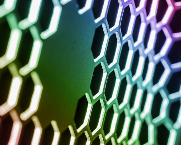 Microscopic view of graphene layers forming hexagonal patterns illuminated with technological green lighting.