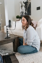 woman in white long sleeve shirt and blue denim jeans sitting on white couch