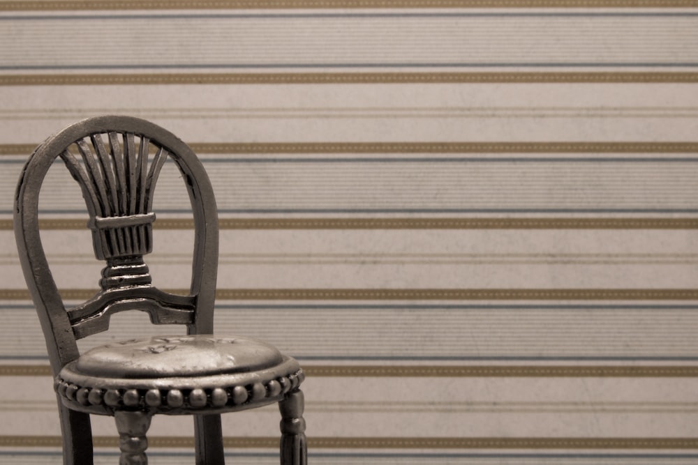 chaise en bois noir à côté d’un mur blanc