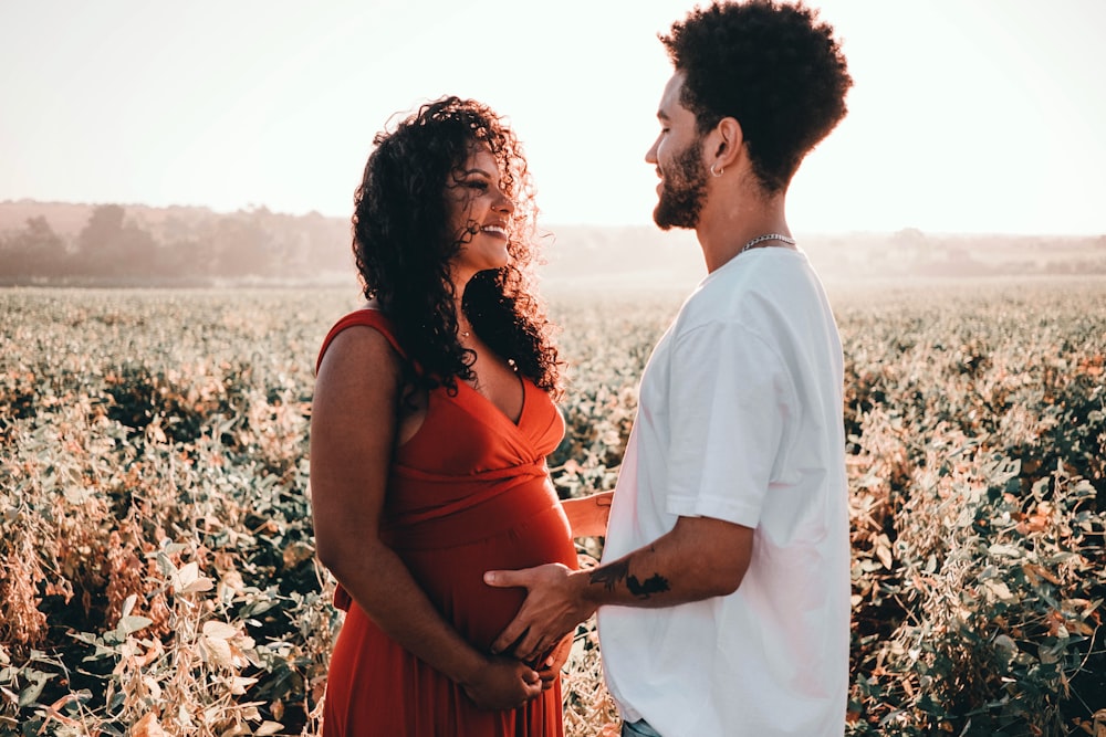 man in white dress shirt and woman in red tank top standing on white flower field