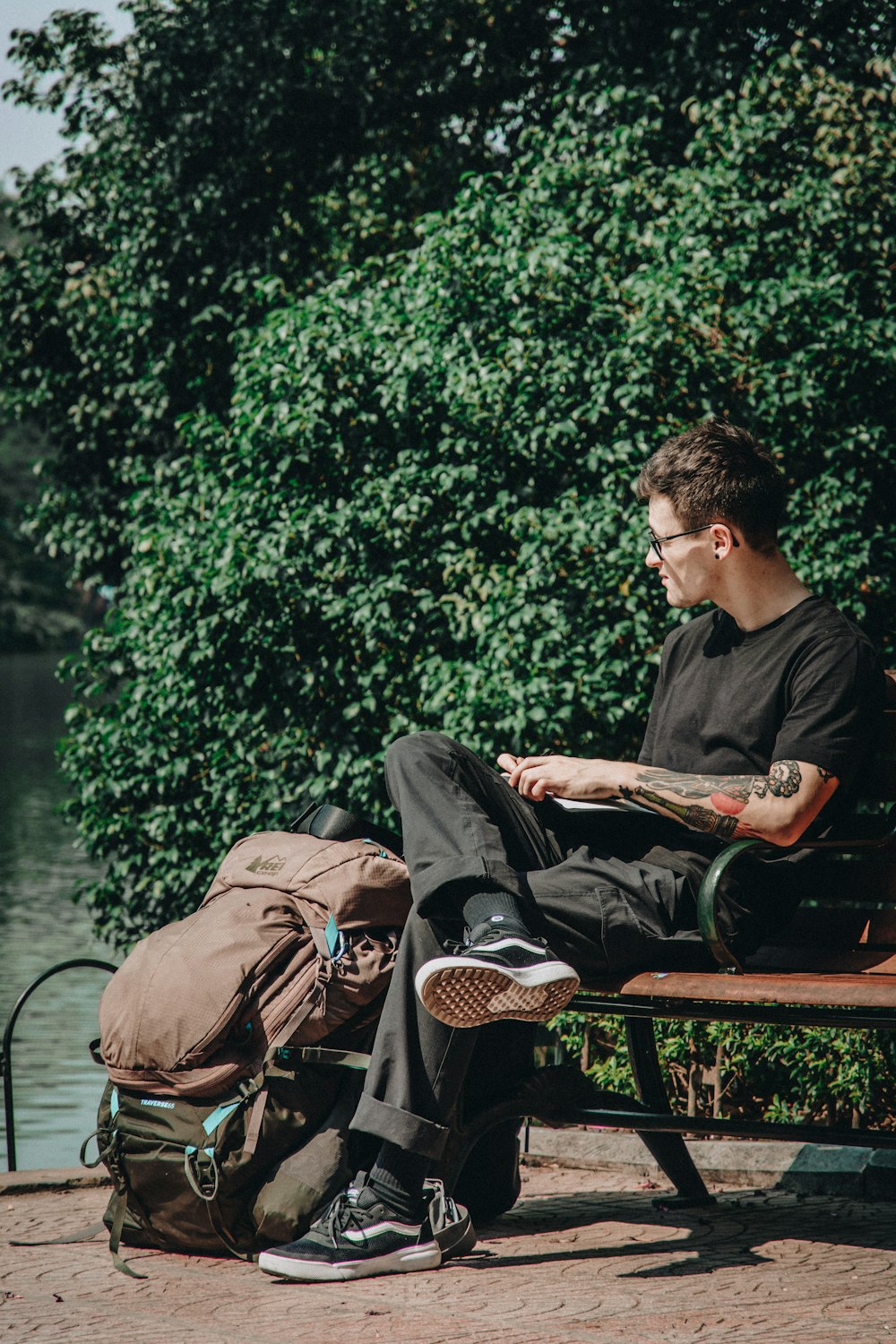 man in black jacket sitting on brown wooden bench