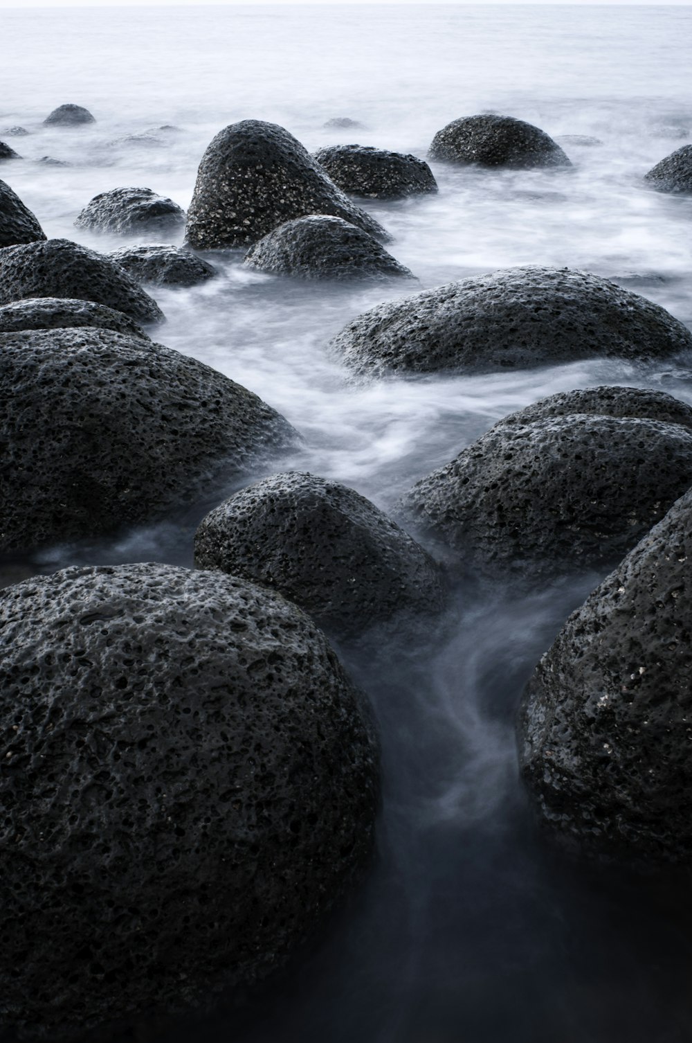 black rock formation on body of water during daytime