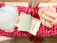 A cozy nook featuring a window seat layered with soft cushions in muted earth tones and a chunky knit blanket.