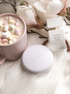 A cozy scene of a perfume bottle next to a handwritten note and a cup of tea.