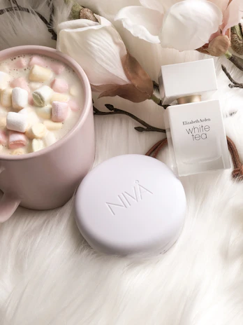 A cozy scene of a perfume bottle next to a handwritten note and a cup of tea.