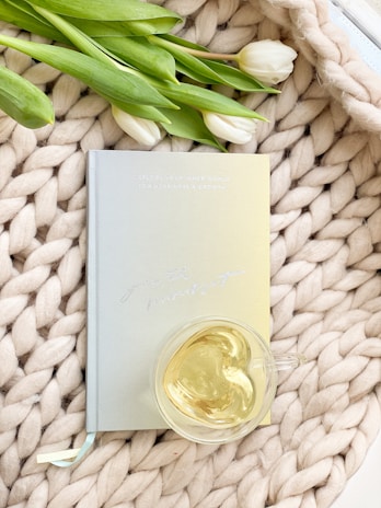 Stacked eggshell notebooks with subtle embossing, placed beside a warm cup of tea.