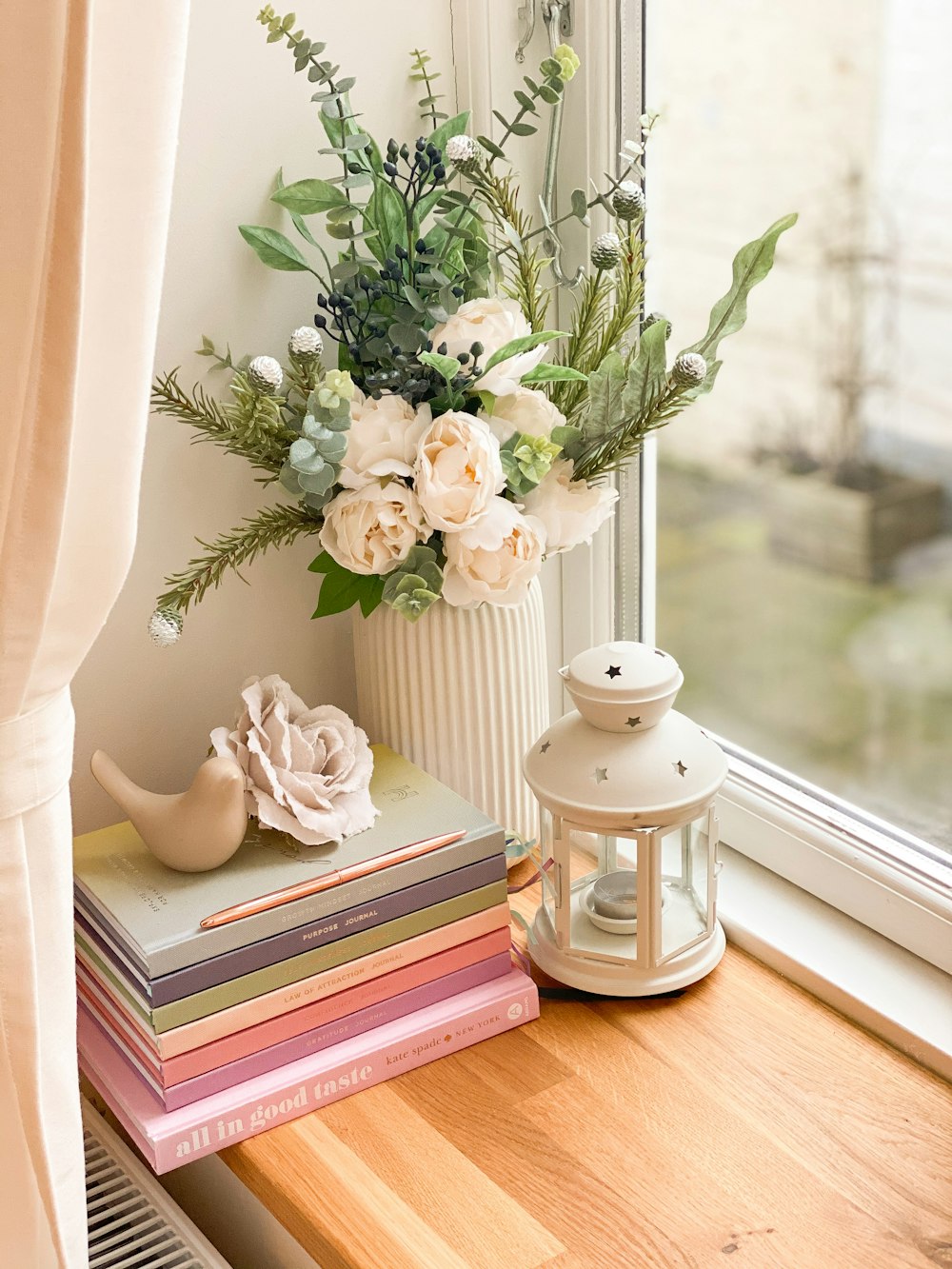 white ceramic vase with white roses on brown wooden table