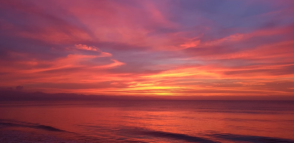 body of water under cloudy sky during sunset