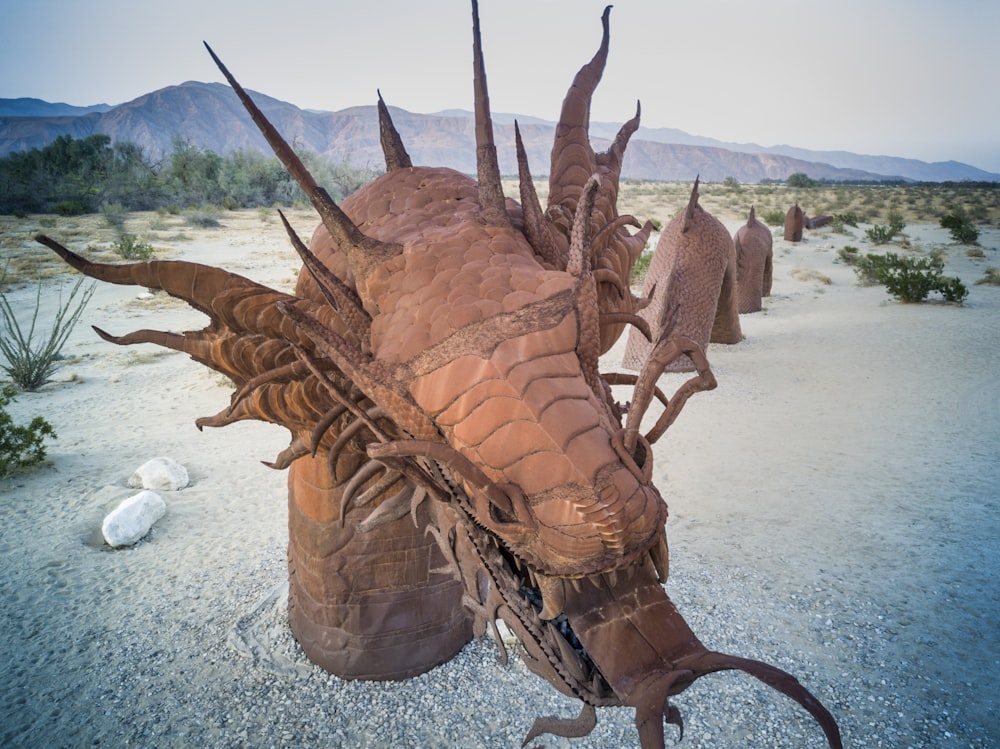 brown wooden animal sculpture on gray sand during daytime