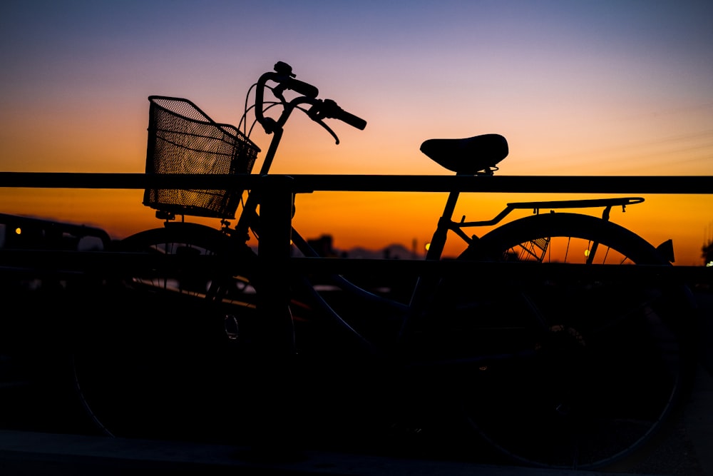 black bicycle beside black steel fence during sunset