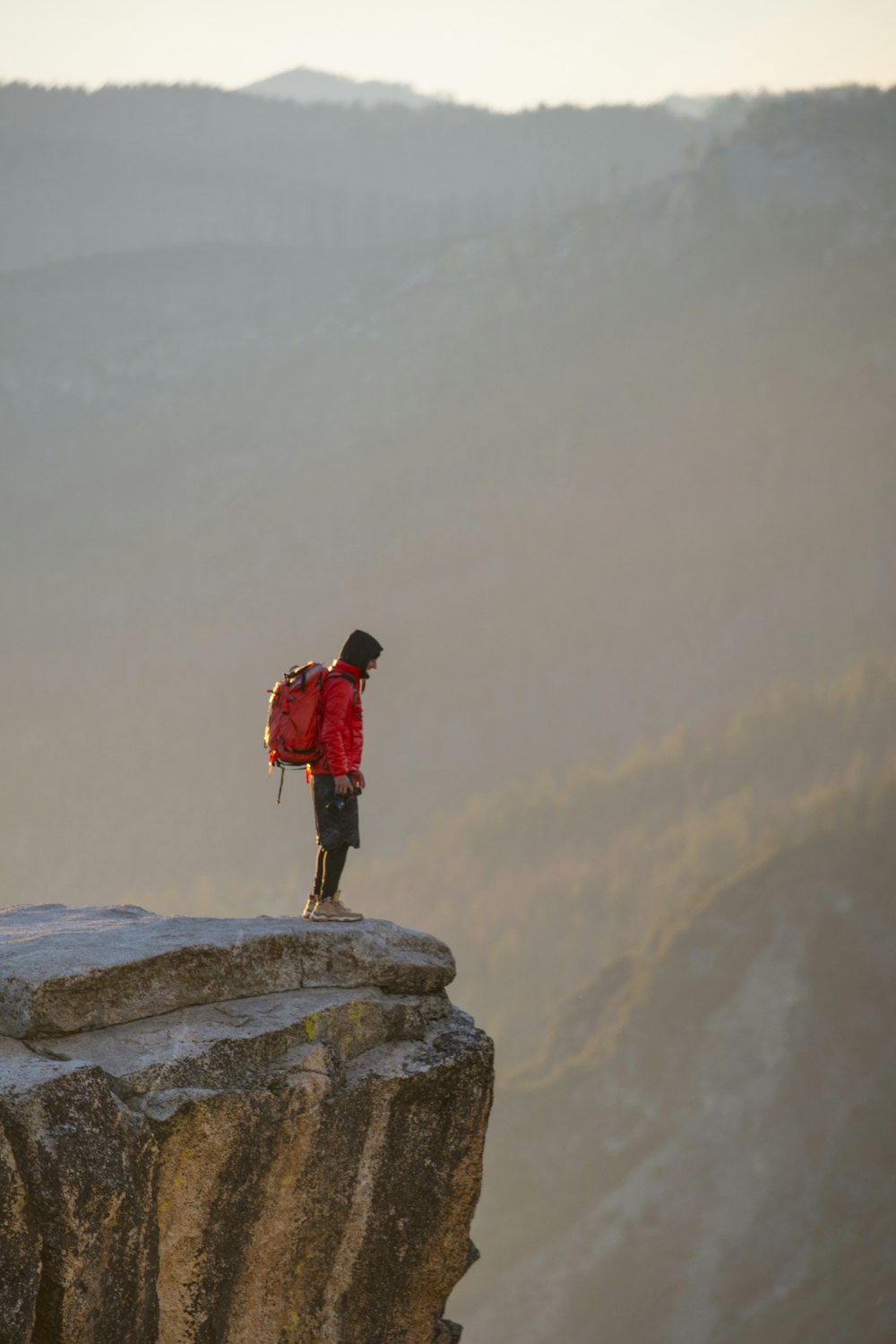 man in red jacket standing on rock formation during daytime