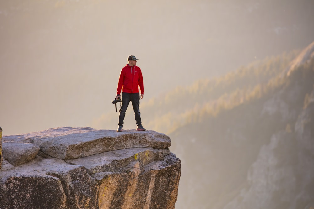 man in red jacket standing on rock formation during daytime