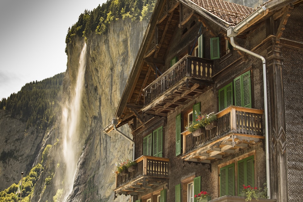 brown wooden house near waterfalls during daytime