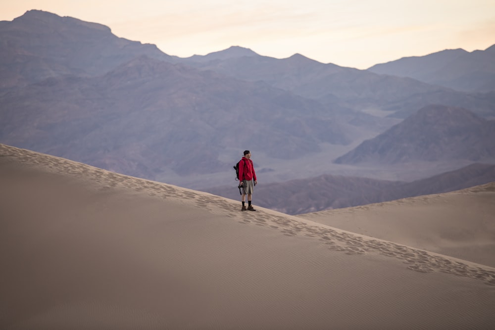 man in red jacket walking on sand during daytime