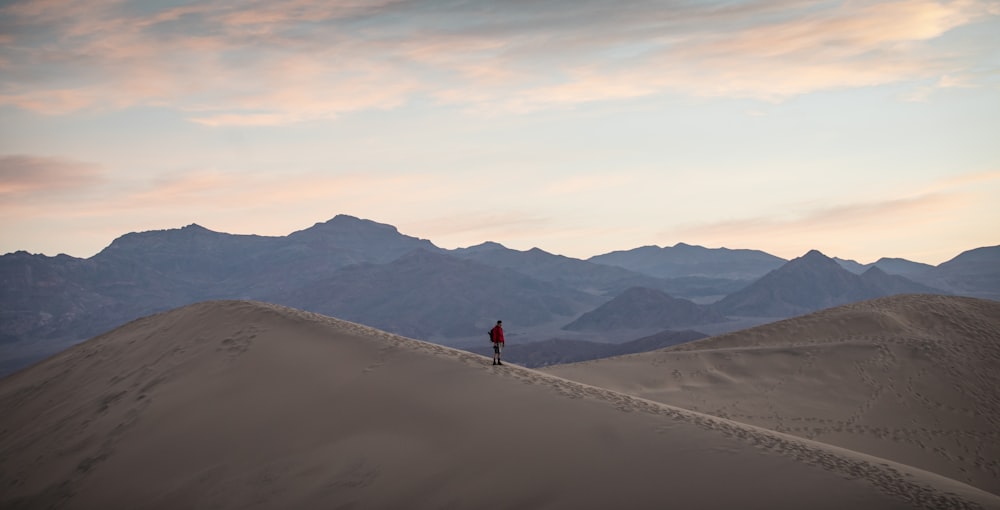 person in red shirt walking on sand during daytime