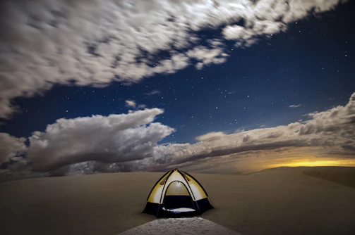 An adventurous traveler camping under a star-filled night in the desert.
