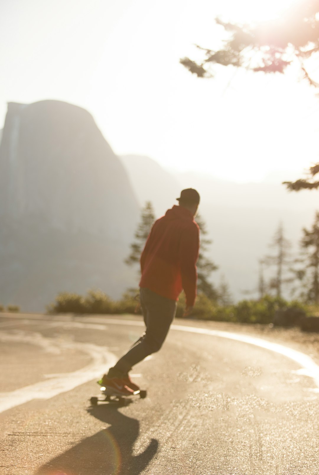 man in red hoodie and black pants walking on brown sand during daytime