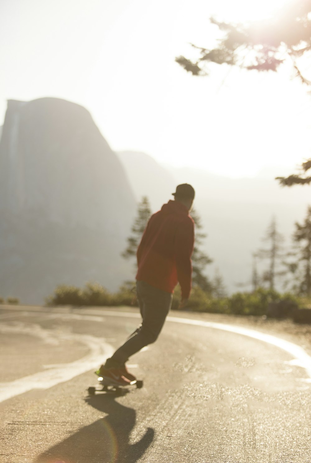 man in red hoodie and black pants walking on brown sand during daytime