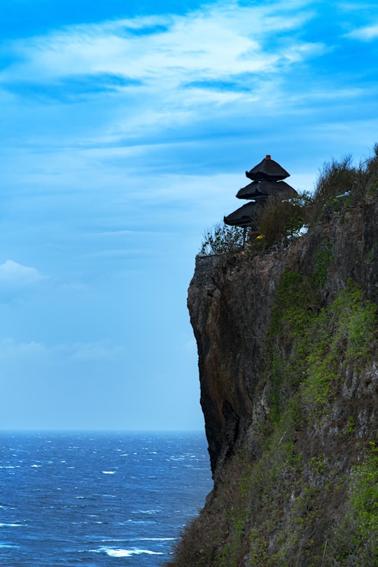 person sitting on rock formation near sea during daytime in Ulu Watu Cliffs Indonesia