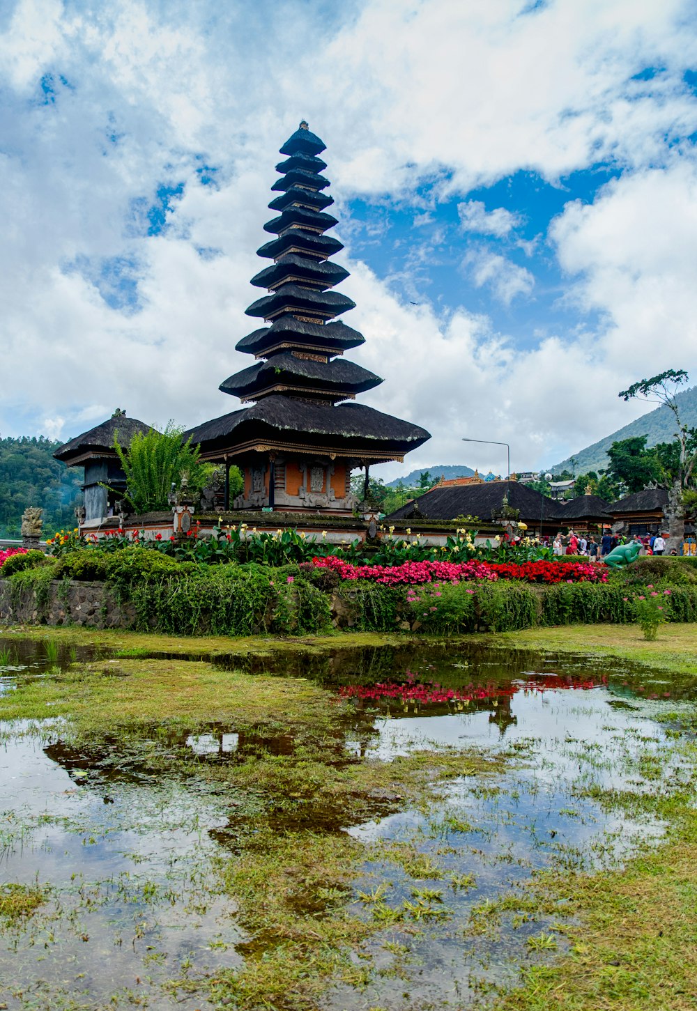 black and white pagoda temple near green grass field under blue and white cloudy sky during