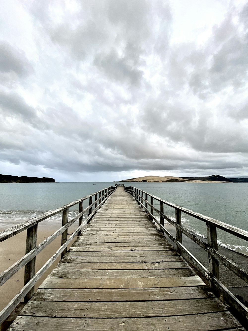 brown wooden dock on sea under white clouds during daytime