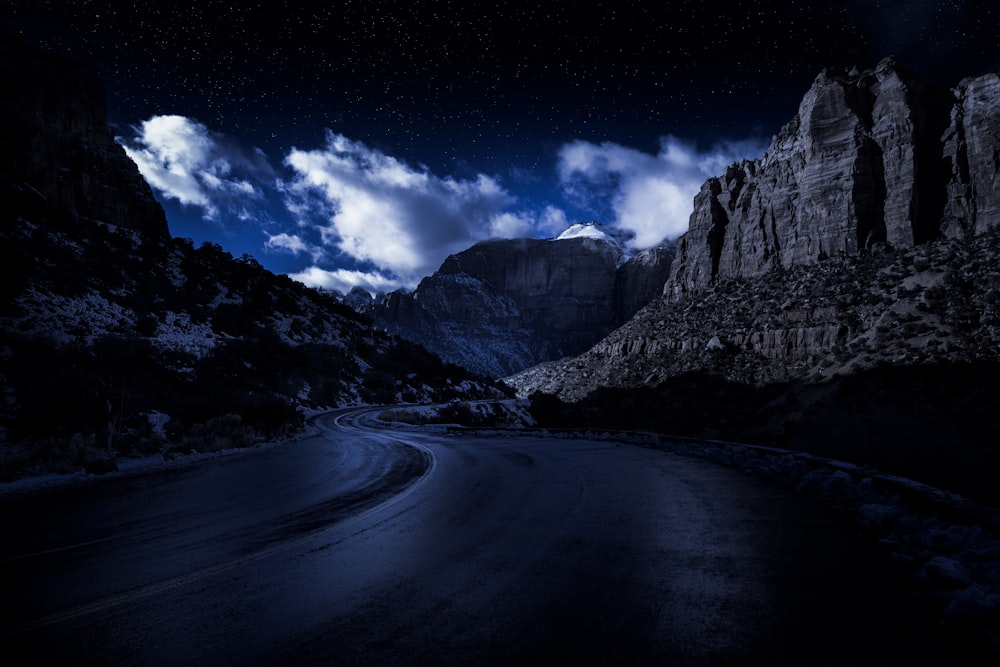 Carretera gris entre montañas rocosas grises bajo cielo azul durante el día