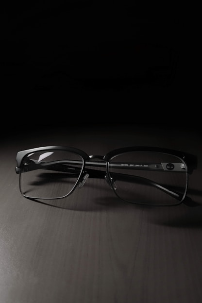 A sleek black and gold luxury eyewear frame resting on a pristine white surface, softly lit to emphasize elegance and precision craftsmanship.
