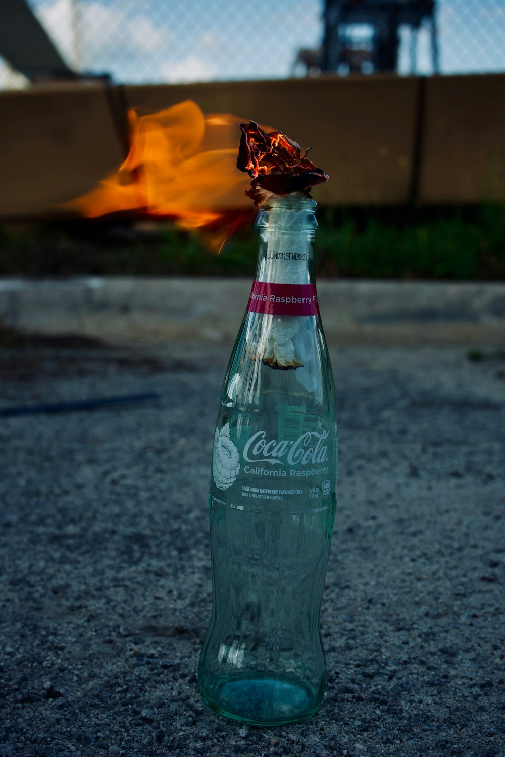 green plastic bottle on gray asphalt road during daytime