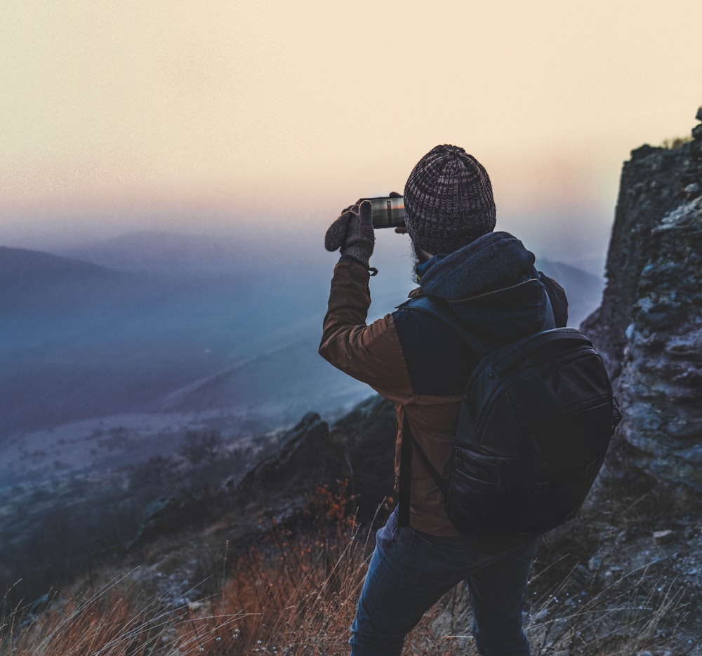 man in black jacket holding black dslr camera