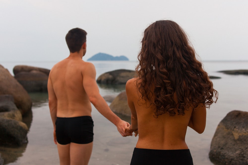 man and woman standing on beach during daytime