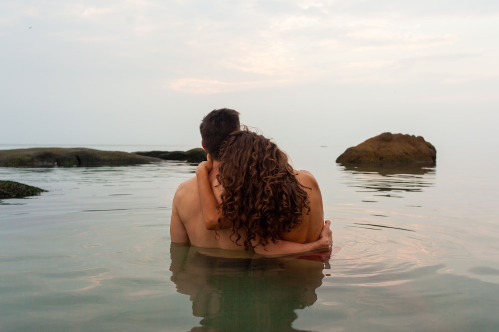 topless man sitting on water during daytime