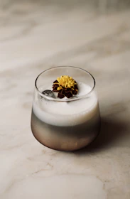A glass of Fruvera poured with a frothy head, set against a backdrop of fresh fruits and brewing equipment.