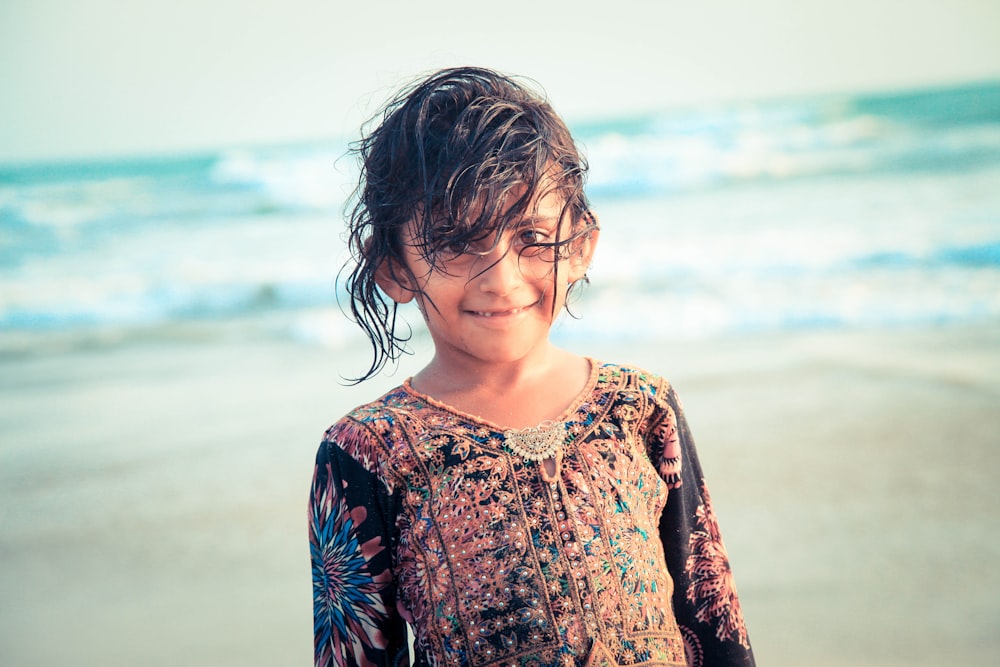 girl in red and black floral crew neck long sleeve shirt standing on beach during daytime