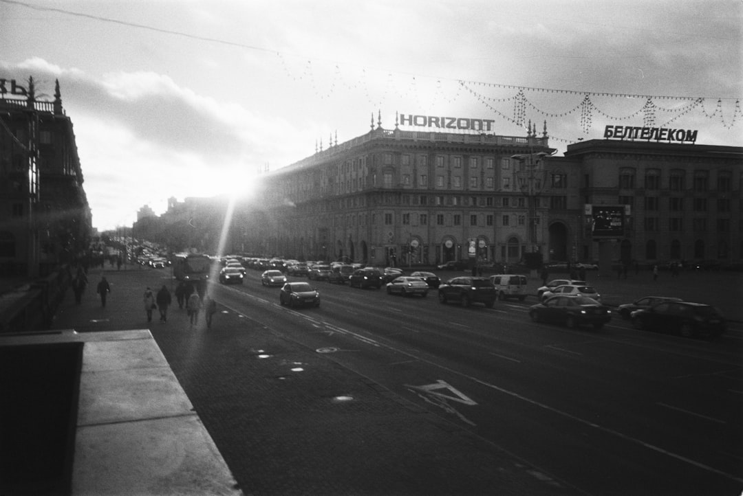 grayscale photo of cars on road near building