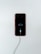 A smartphone with a red exterior is connected to a charging cable. The phone's screen displays a low battery icon with a charging symbol beneath it, indicating that the device is in the process of recharging.