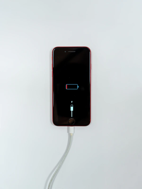 Red iPhone SE connected to a charging cable