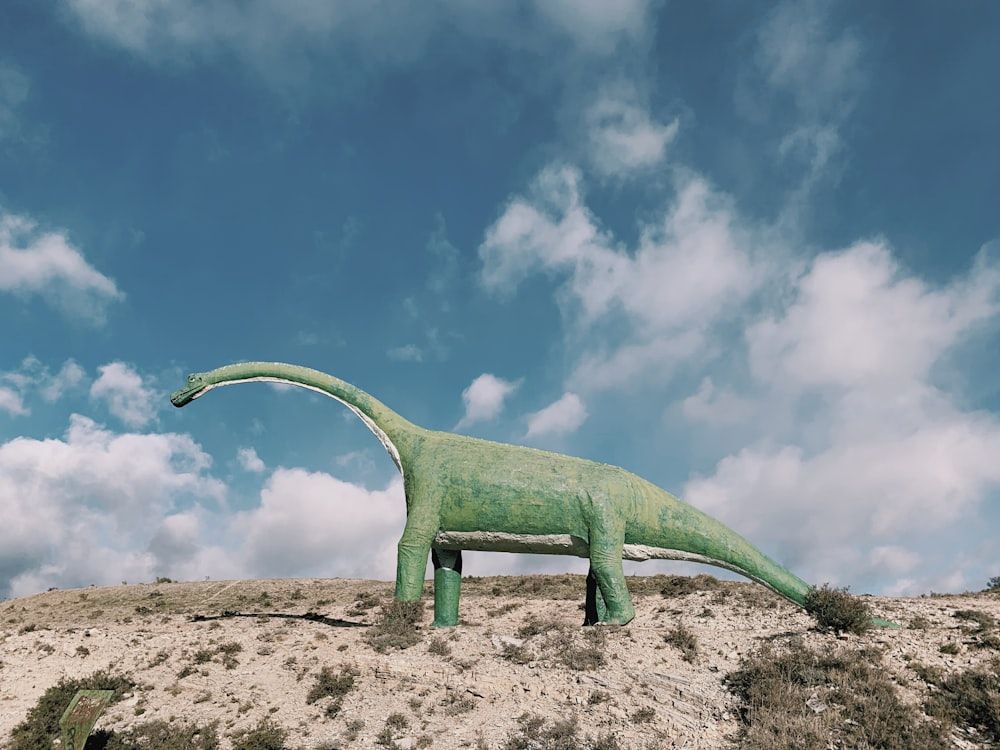 green dinosaur on brown sand during daytime