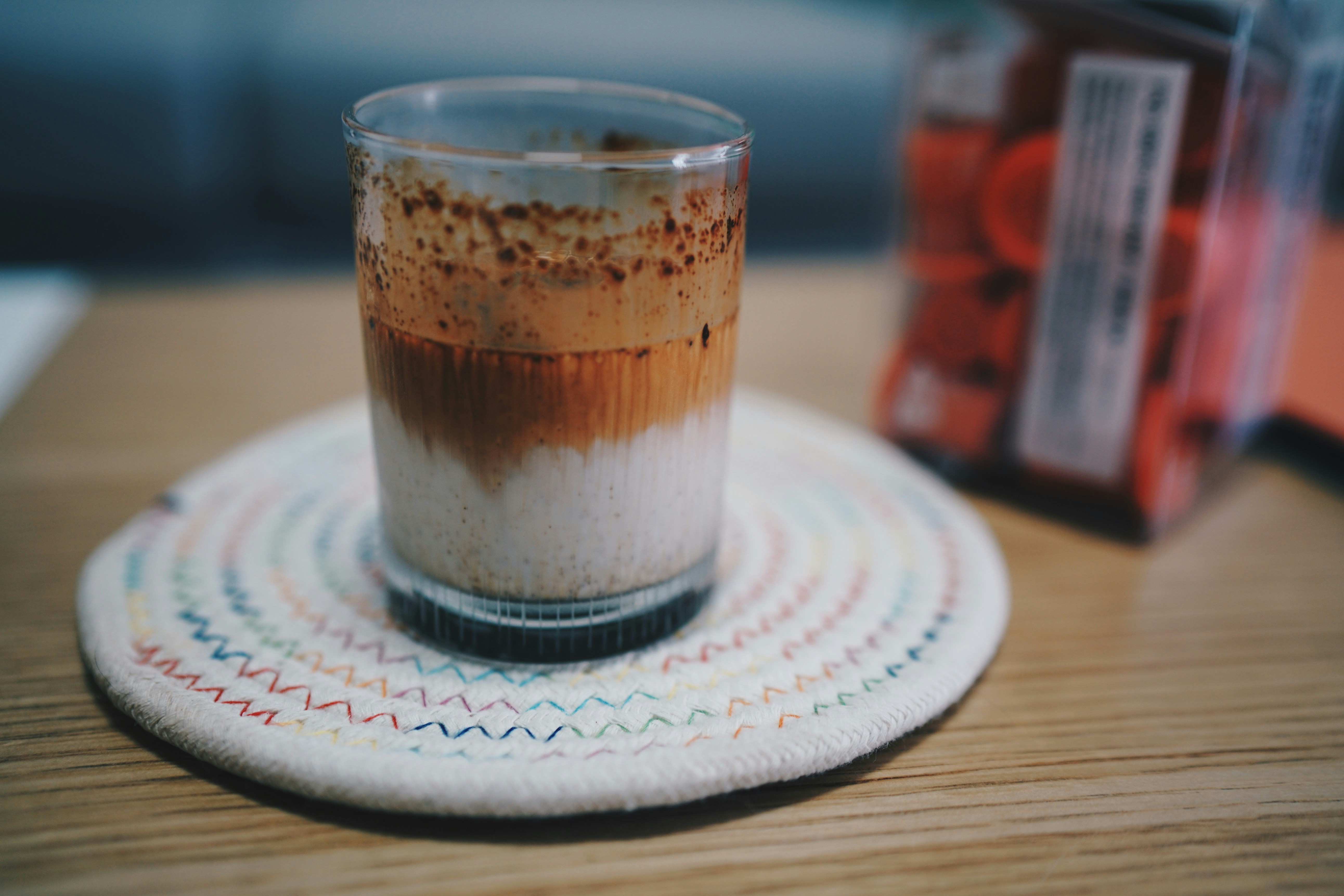 Layered iced coffee in a glass on a woven coaster