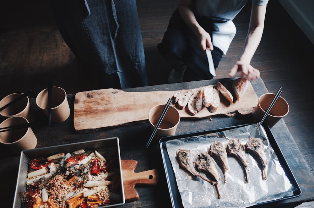 person slicing fish on brown wooden chopping board