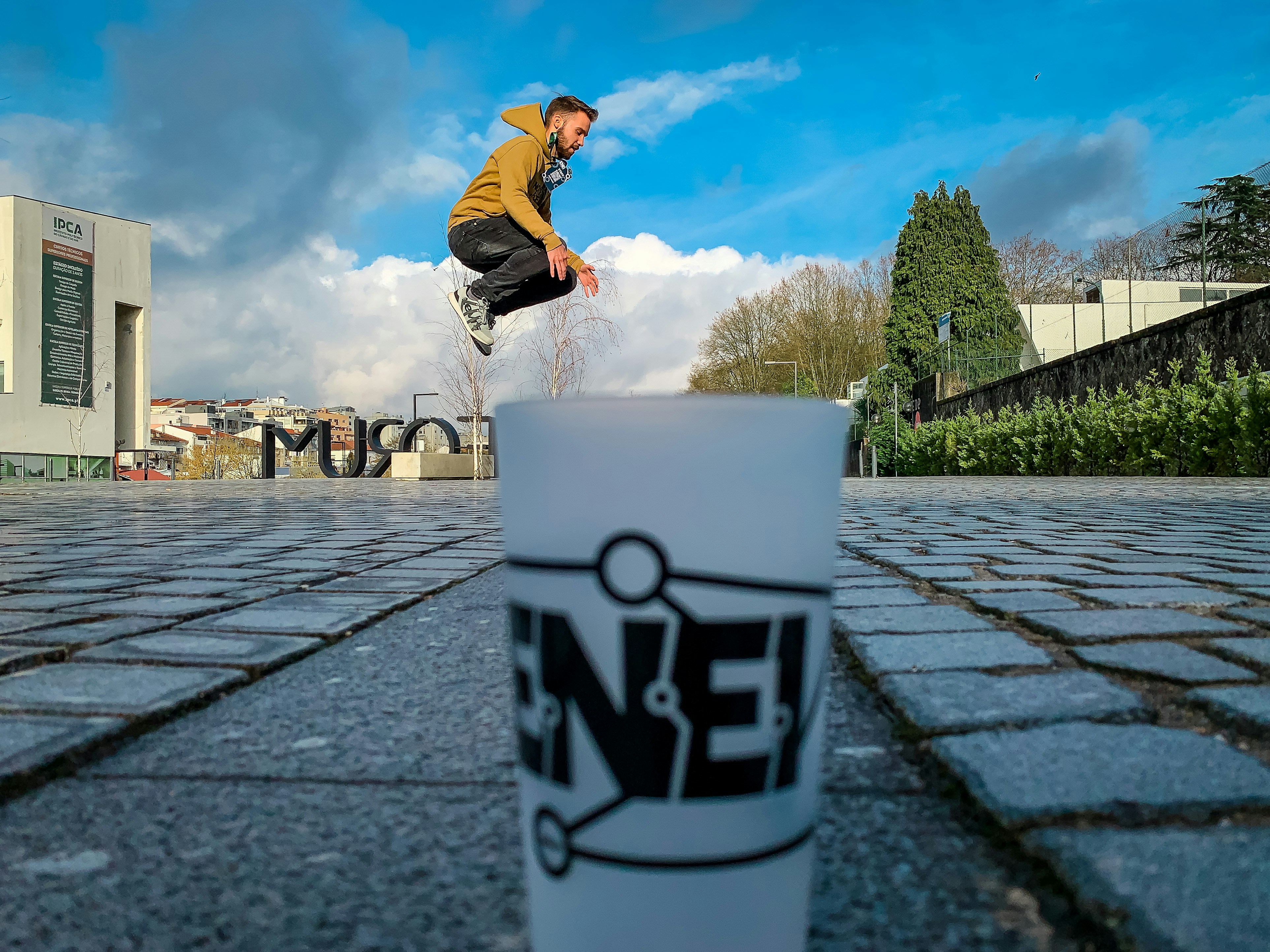 man in black jacket and blue denim jeans jumping on water fountain during daytime